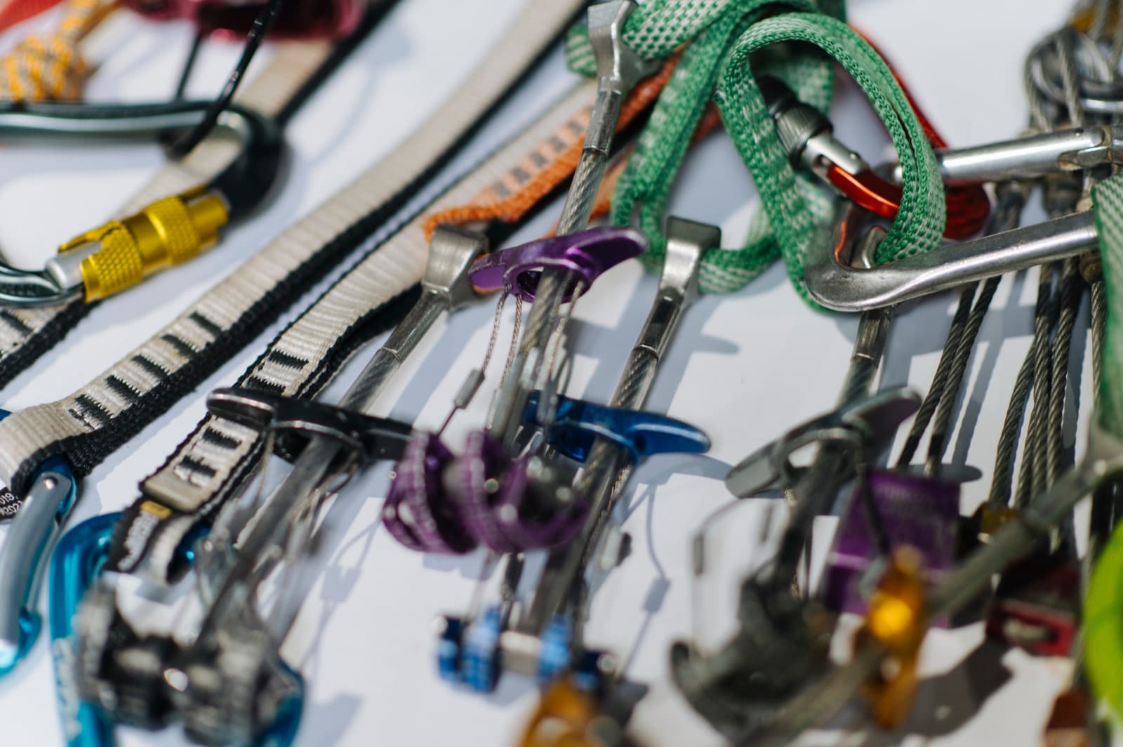 A flat lay of climbing gear including a harness, carabiners, a belay device and a rope.