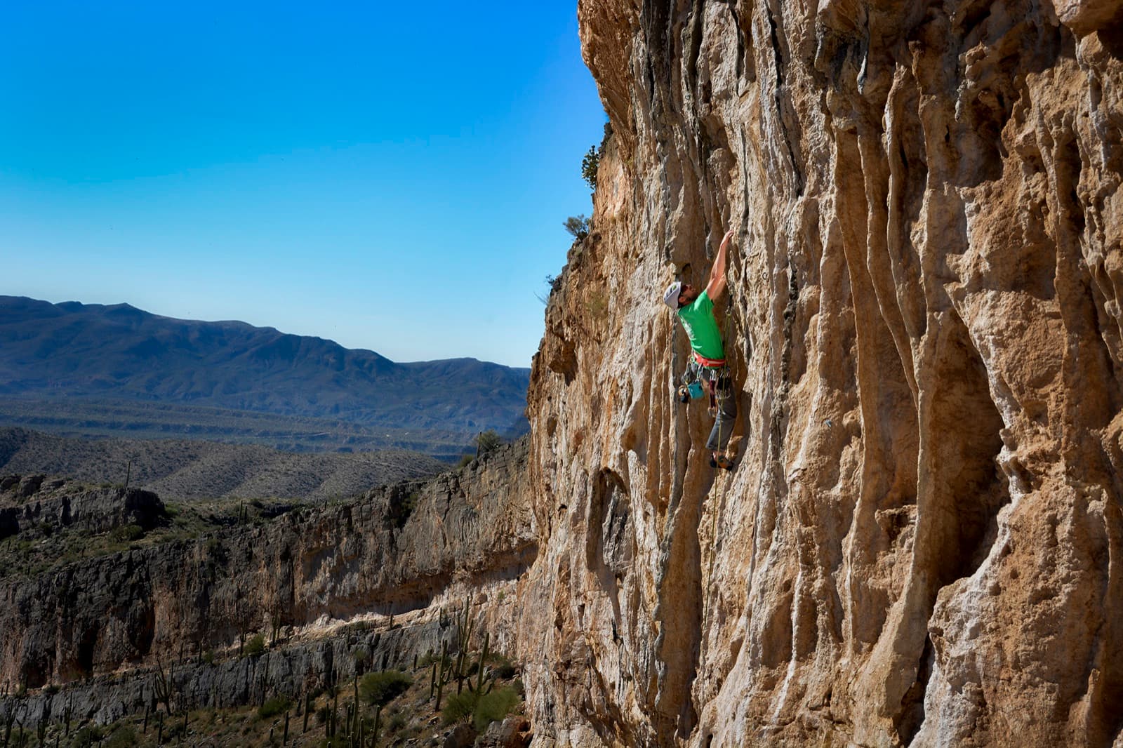 A climber working up a steep rock face on an outdoor route.