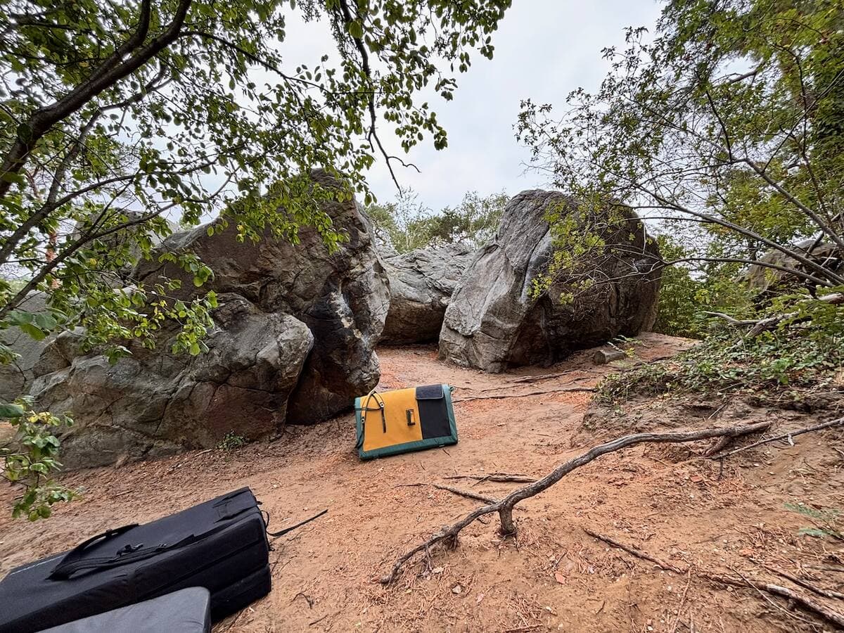Two large boulders in woodland at Langenstein, with a yellow crash pad leaning against the rock and a second pad in the foreground.