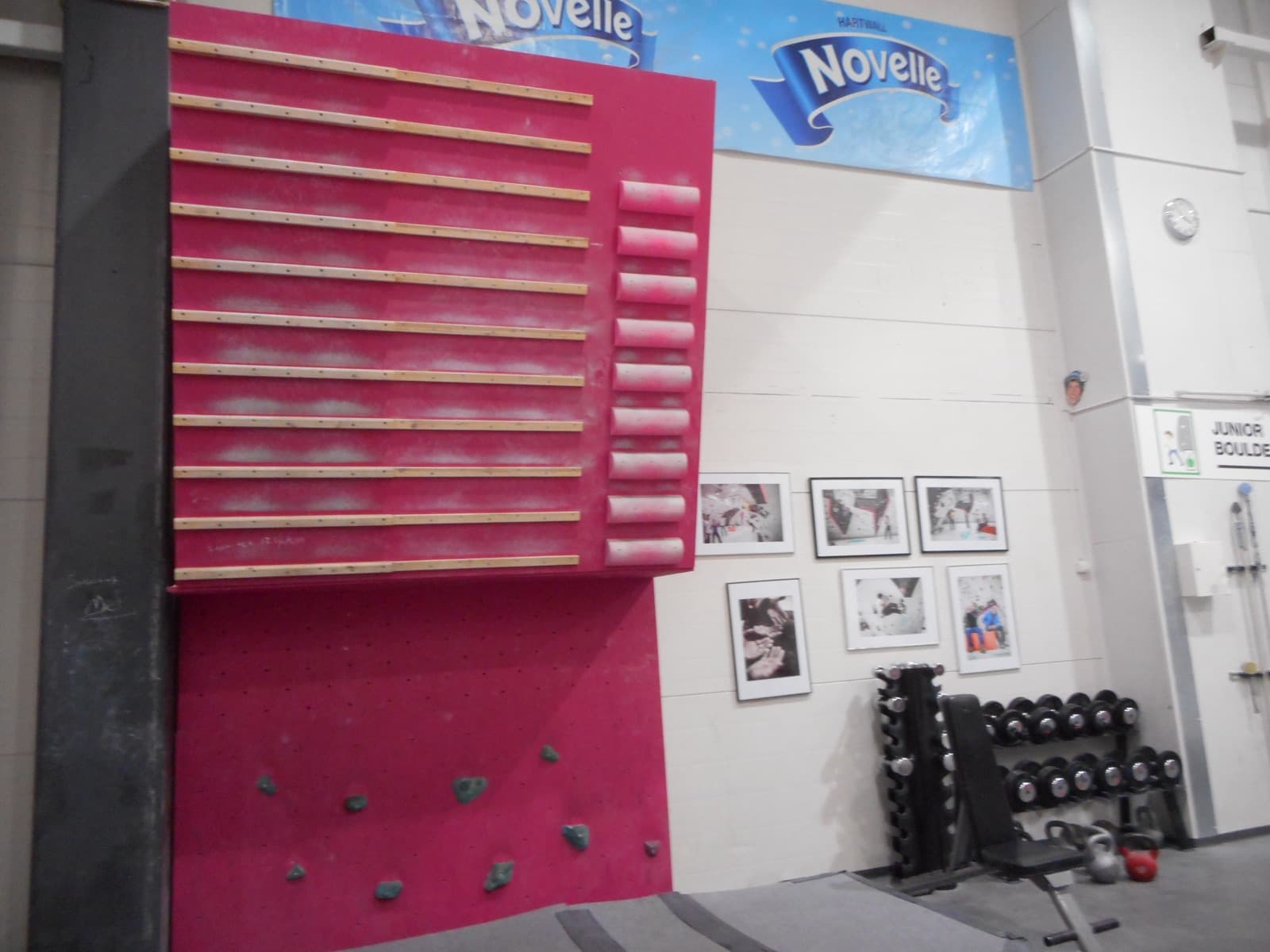 A climber training on a wooden campus board in a gym.