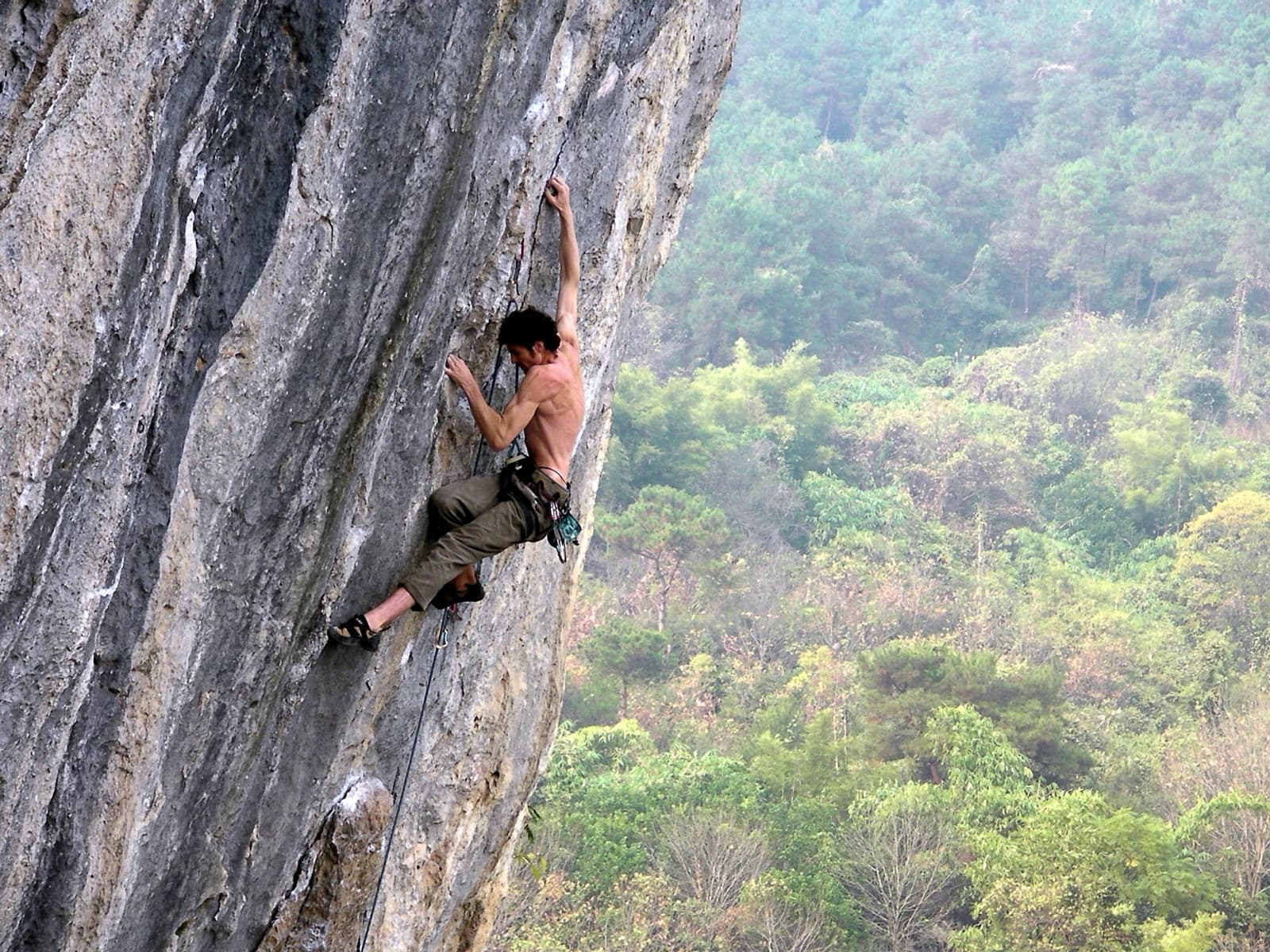 A climber high on a large limestone cliff in Yangshuo, China.