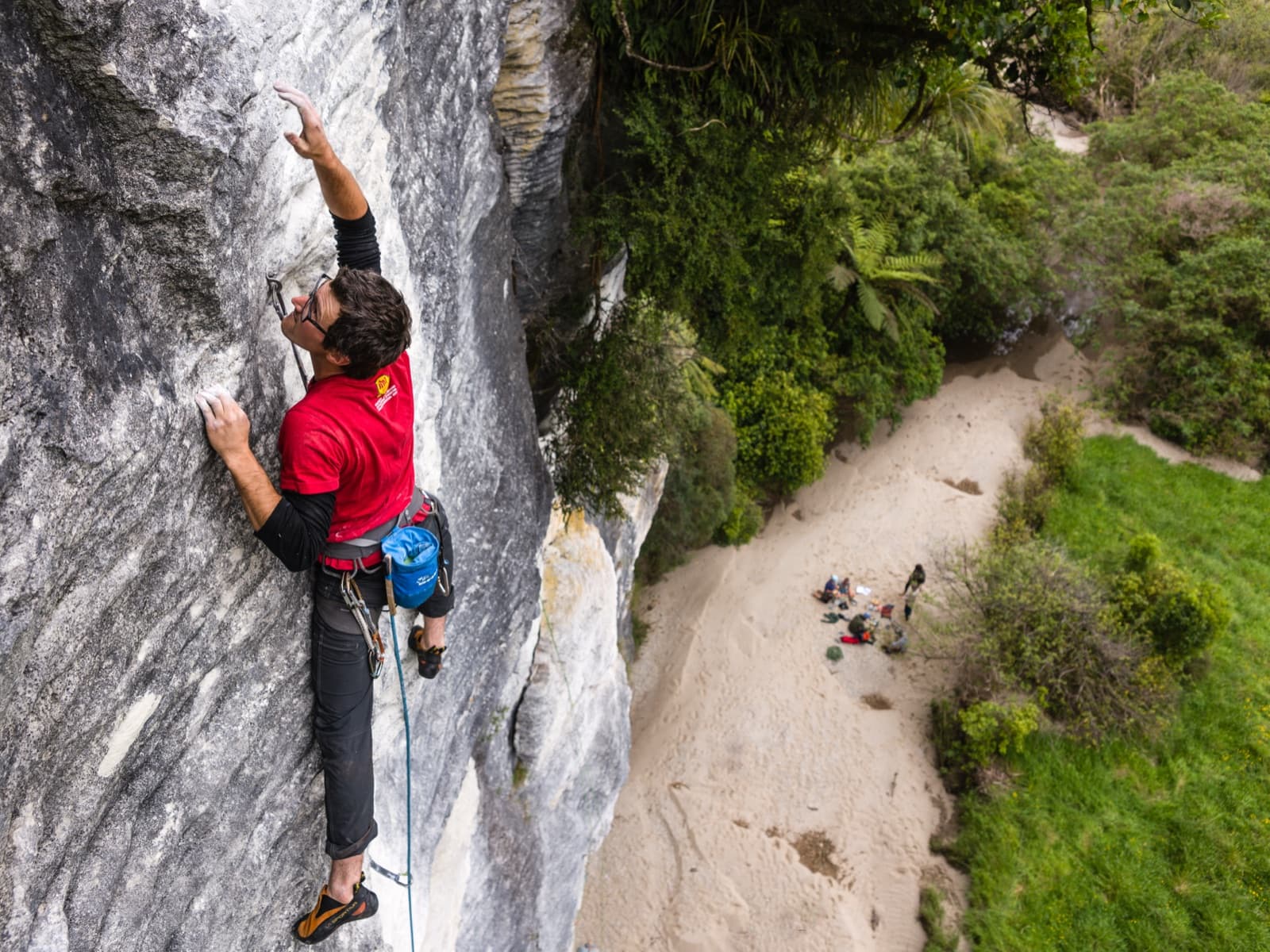 A climber high on a steep rock face with a long drop below.