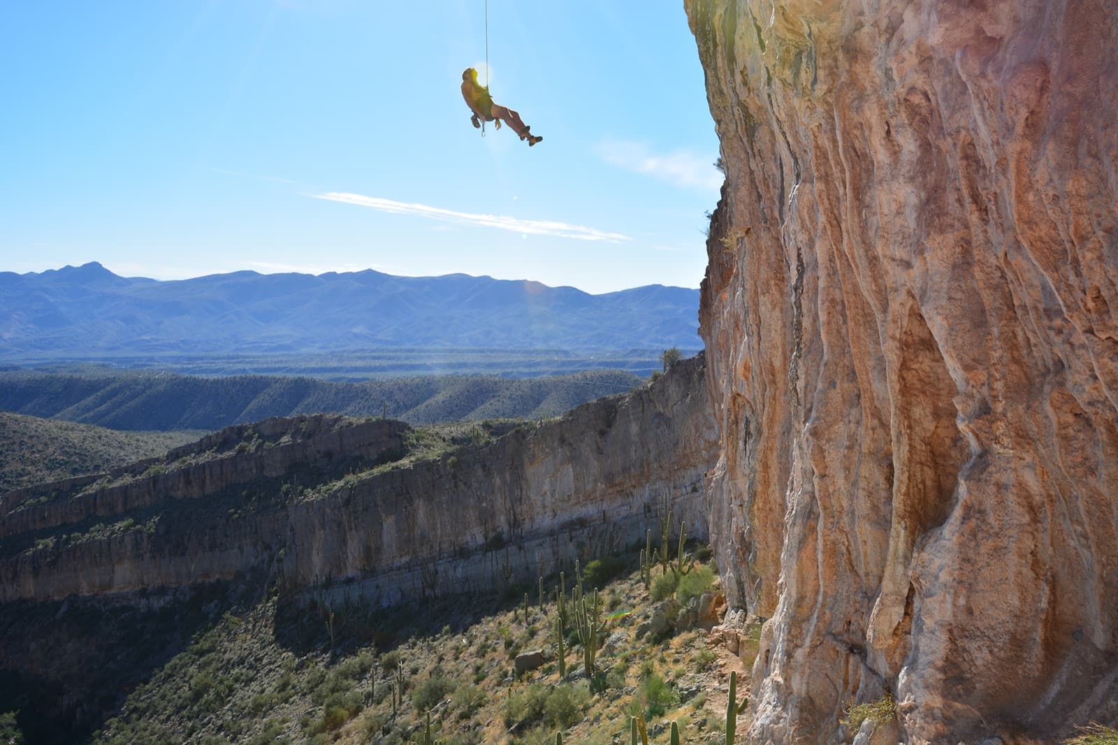 A roped climber pausing on a rock wall to read the moves ahead.