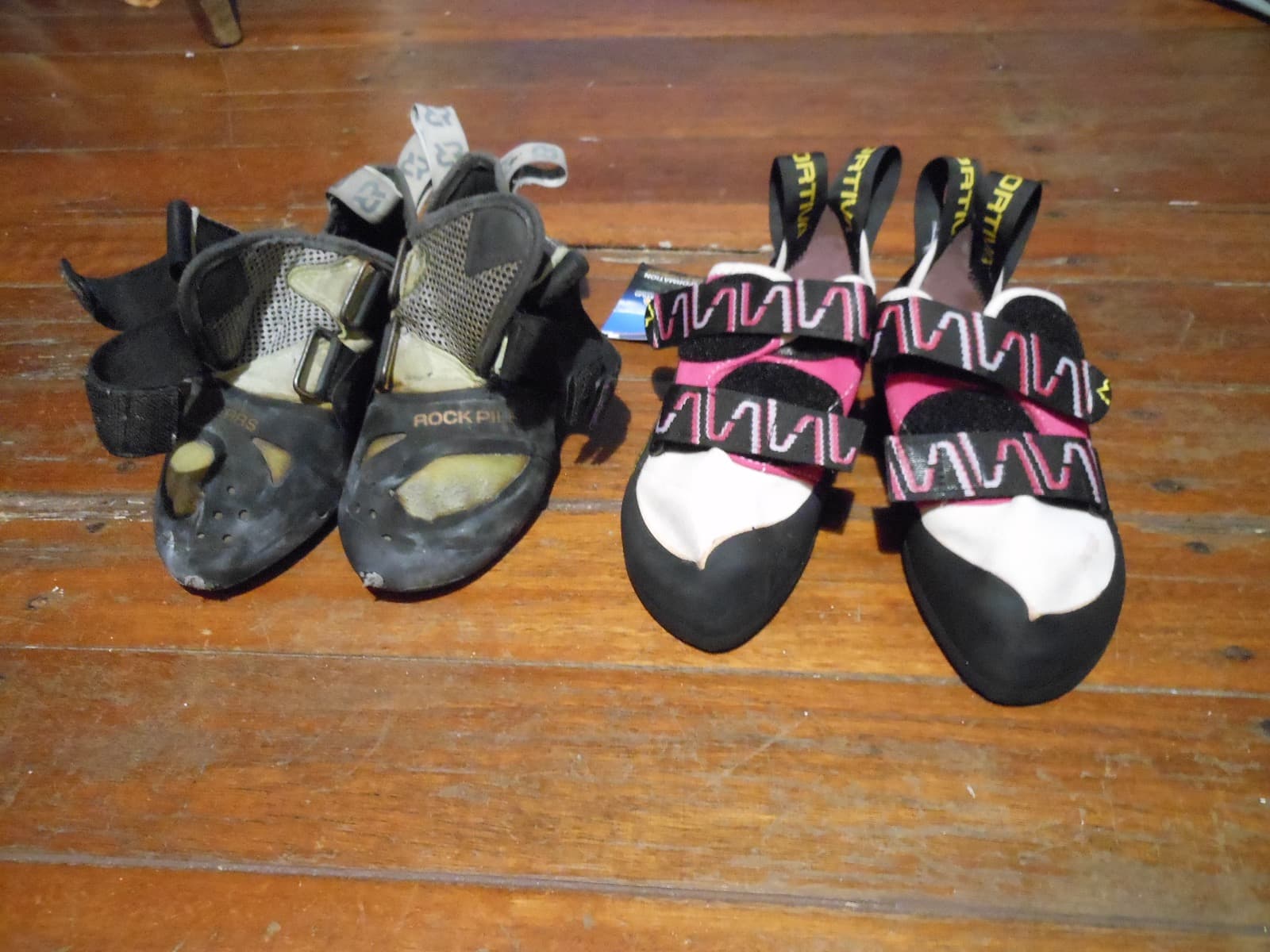 Two pairs of climbing shoes side by side, one well worn and one nearly new.