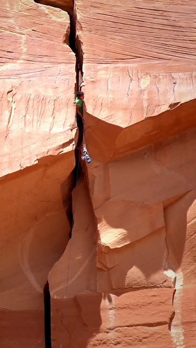 A climber squeezing through the narrow chimney of Liquid Sky on a desert tower