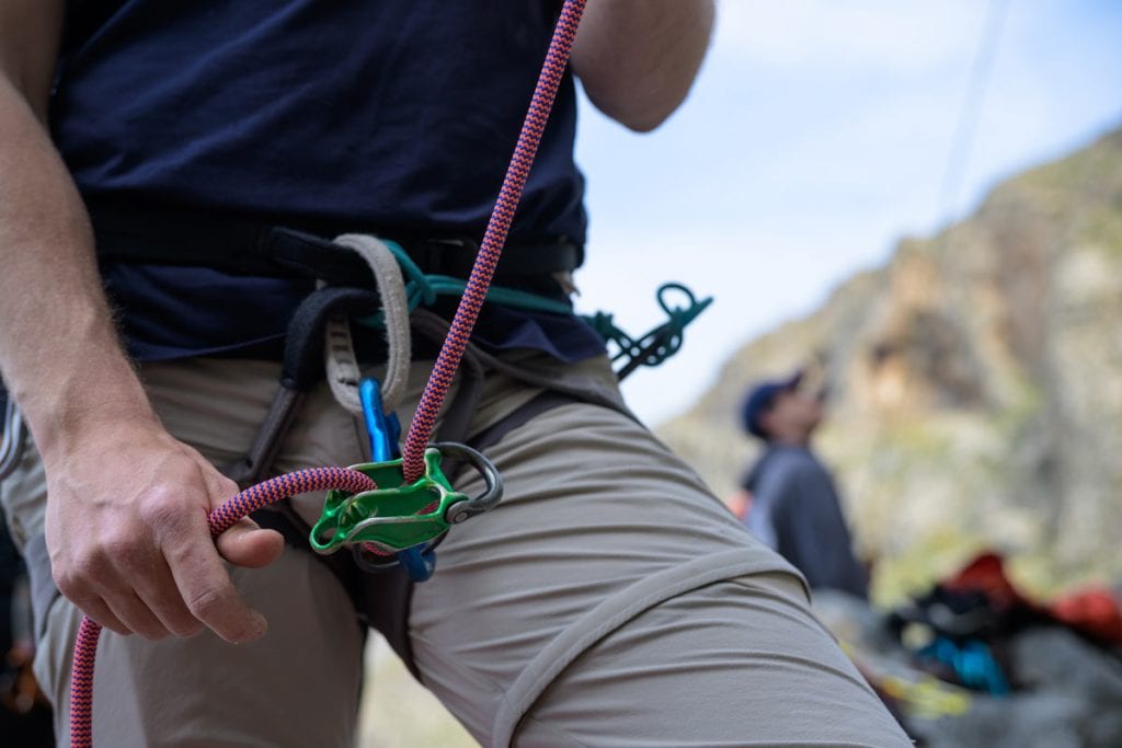 Close up of a climber's harness with a belay device and rope