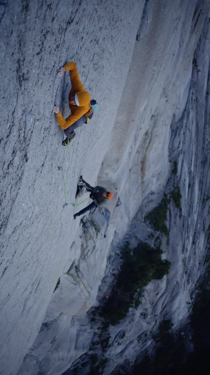 Two climbers on a vast pale granite slab seen from above