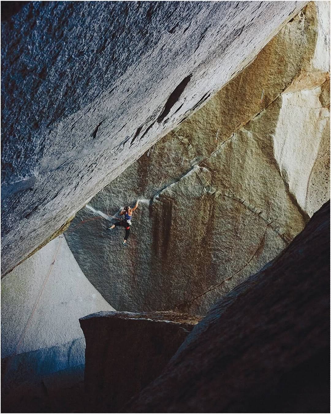 Small figure of a climber beneath a huge overhanging granite roof in Squamish