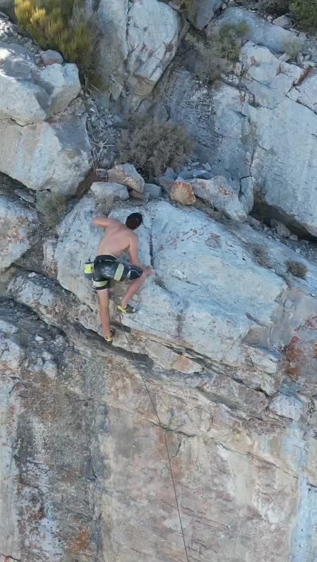 Drone view looking down on a climber on a pale grey limestone face