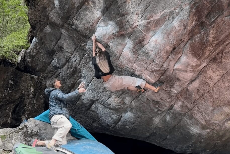 Jana Švecová on a steep granite boulder in Val Daone with a spotter below