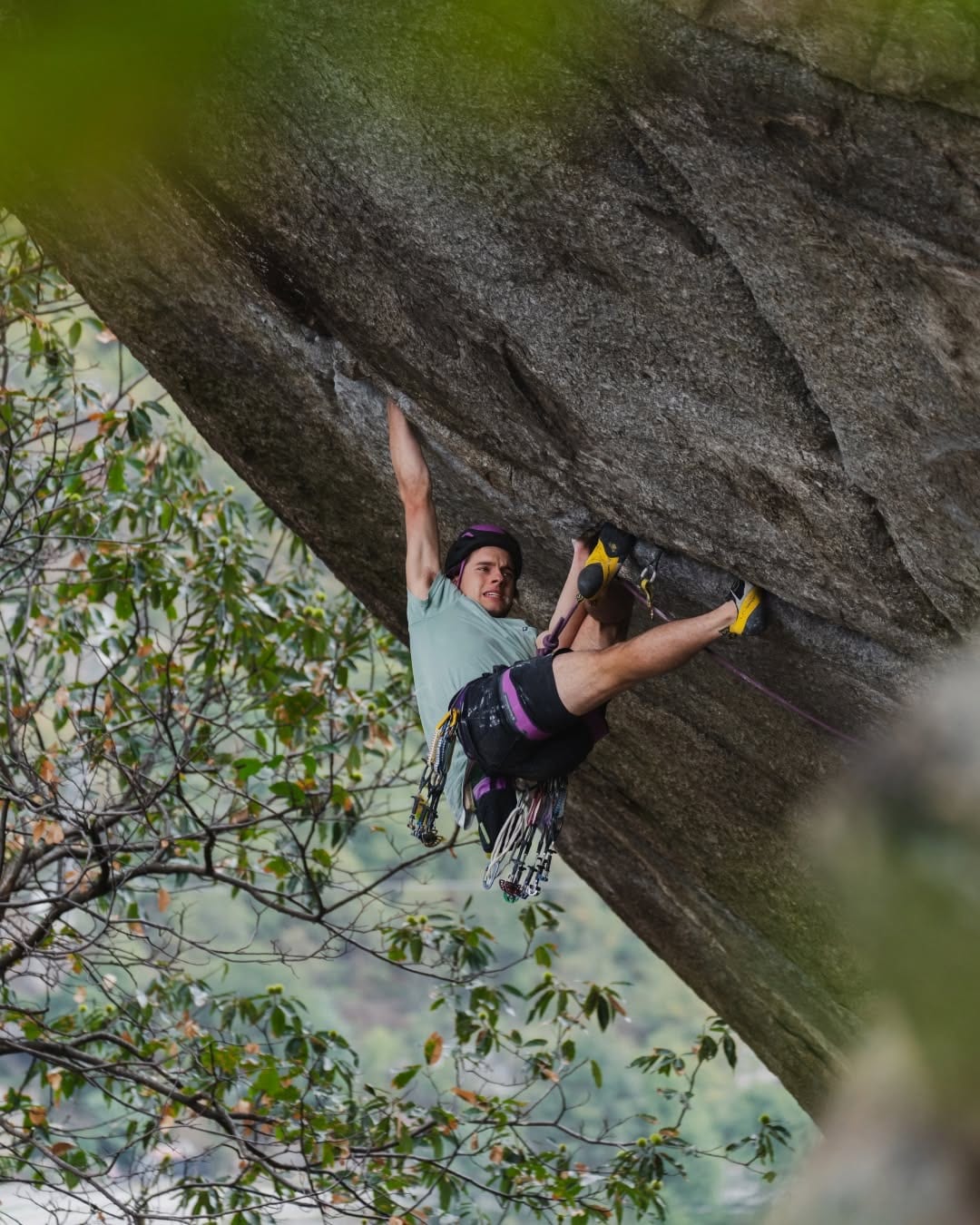 Connor Herson hanging from a jam in the granite roof crack of Greenspit, with trad gear on his harness